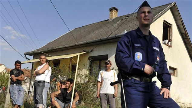 In April 2011, a Hungarian police officer guarded a Roma neighbourhood close to a site where vigilante groups set up a training camp. Threats from vigilantes and discrimination prompted some Roma to flee Hungary. Photo Credit: Bela Szandelszky/AP Photo