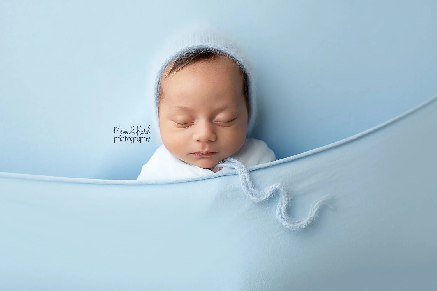 newborn baby boy sleeping with a baby blue wrap