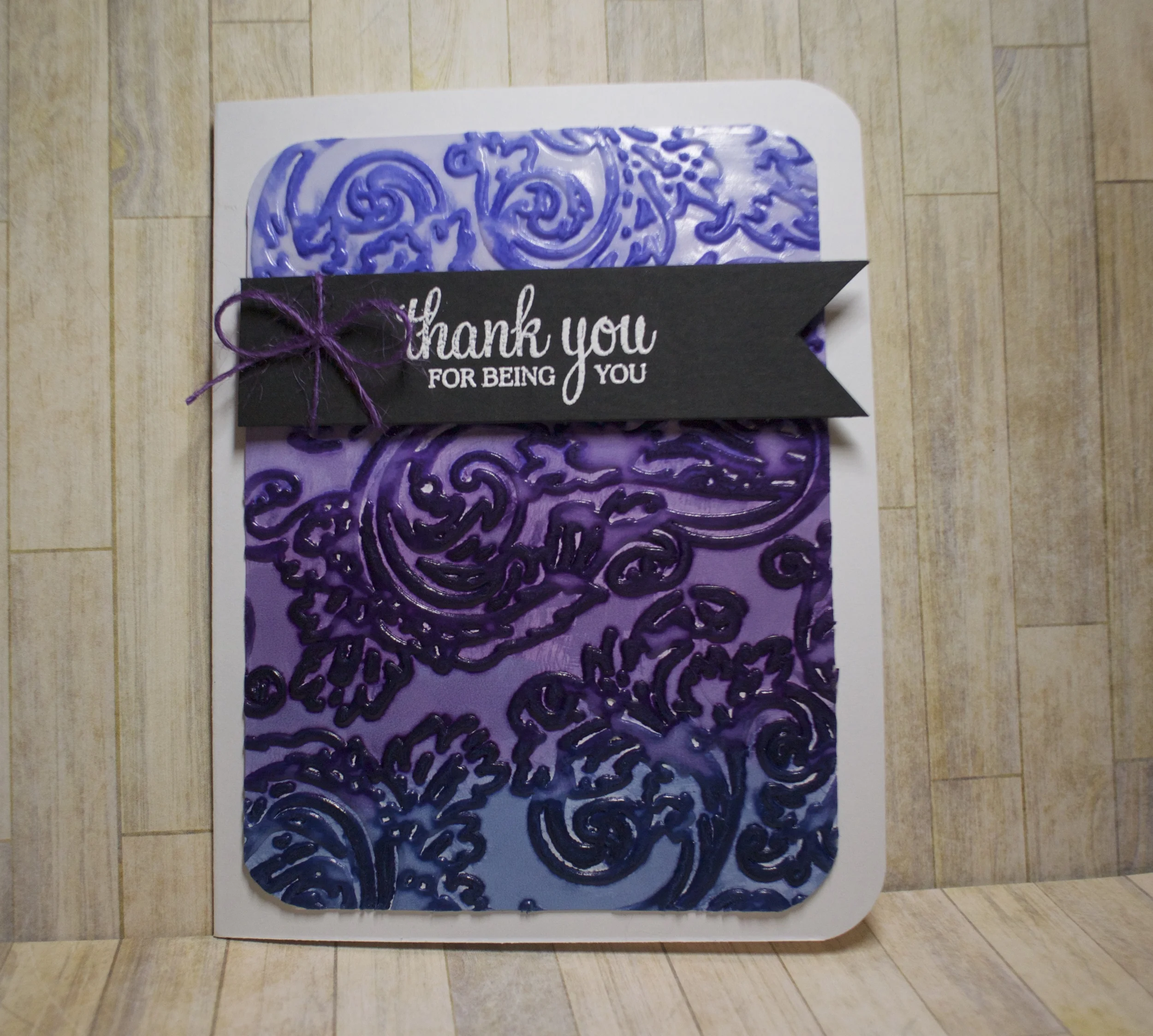 Ranger Glossy card stock dry embossed with a Hero Arts folder and rubbed with Distress Inks Milled Lavender, Seedless Preserves and Faded Jeans then mounted on Nenah Solar White card base. The sentiment is from a Hero Arts set white heat embossed on black Bazzill yardstick and tied with a little piece of purple twine.