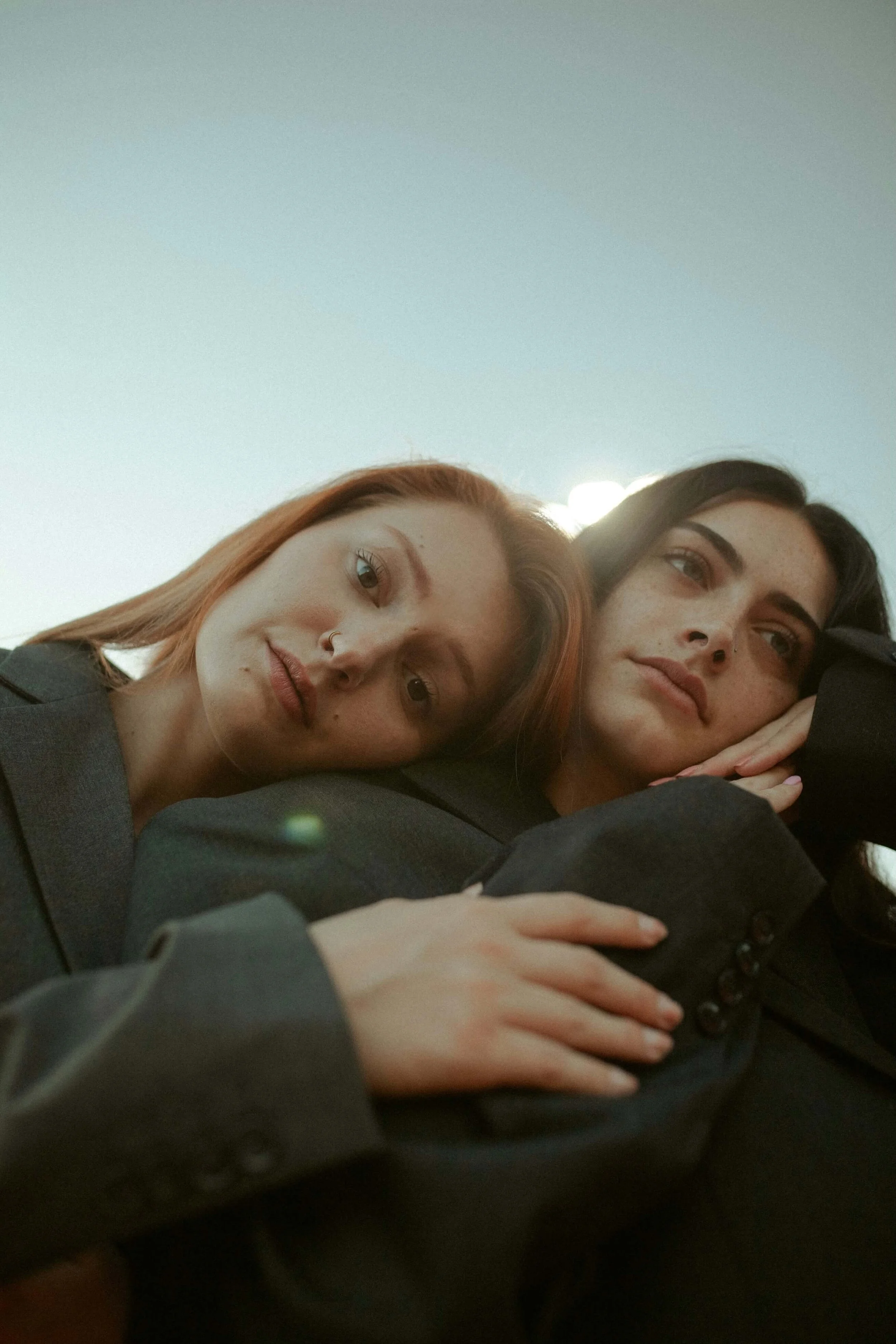 Two women with different hair colors huddle closed together, appearing relaxed and comfortable.