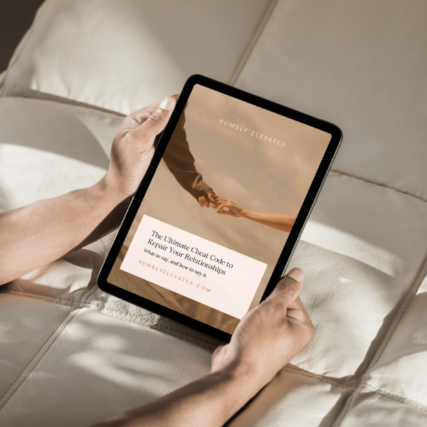 Person holding tablet displaying a guide about repairing relationships, titled 'HUMBLY ELEVATED', with a background image of two hands reaching out.