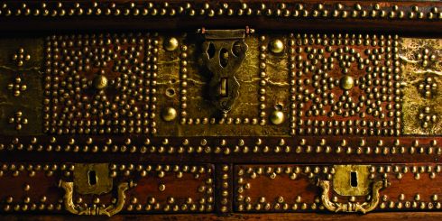 In the majority of local (Southern Arabia) households prior to the start of modern development around 1950, chests were the only form of furniture and therefore are one of the few truly indigenous antiques. Not only did they form a functional purpose but were also used as a medium for the expression of decorative art. Like the treasures they once held within their dark and woody depths, the beautiful hand made chests once used during the past several centuries across the Arabian peninsular, are becoming more rare with each passing year. No two chests are exactly alike and every one should be considered a work of art in its own right. The oldest chests available at Showcase date back to the arrival of the Portuguese in Oman in the early 16th century. Made of Brazilian mahogany and often secured with a complex iron clasp and lock, they belonged to Portuguese officers, administrators and traders and were used to store personal possessions and weapons. When the explorers returned home they frequently left the chests behind - a reminder of their presence in that area. The Omanis later copied the style, including the small covered compartments on the inside, however, adjustments were made accordingly. They used teak, rosewood and jackfruit wood instead of mahogany and decorated the chests with dark wood beading, brass flowers, emblems and flat-pressed brass plates with Islamic patterns reflecting the inherent culture of the area. The prized Mandoos chest was the most highly decorated with three or sometimes four drawers at the base and is referred to as a ‘wedding chest’. It is possible to categorise chests by design such as Shiraz, Surat, Bombay, Malibar. These titles are not indicative of the origin but rather reflect their style and therefore they are better categorised by use such as wedding, domestic storage, sea or pearl chests. All our antiques come with a certificate of authenticity stating full description and date.