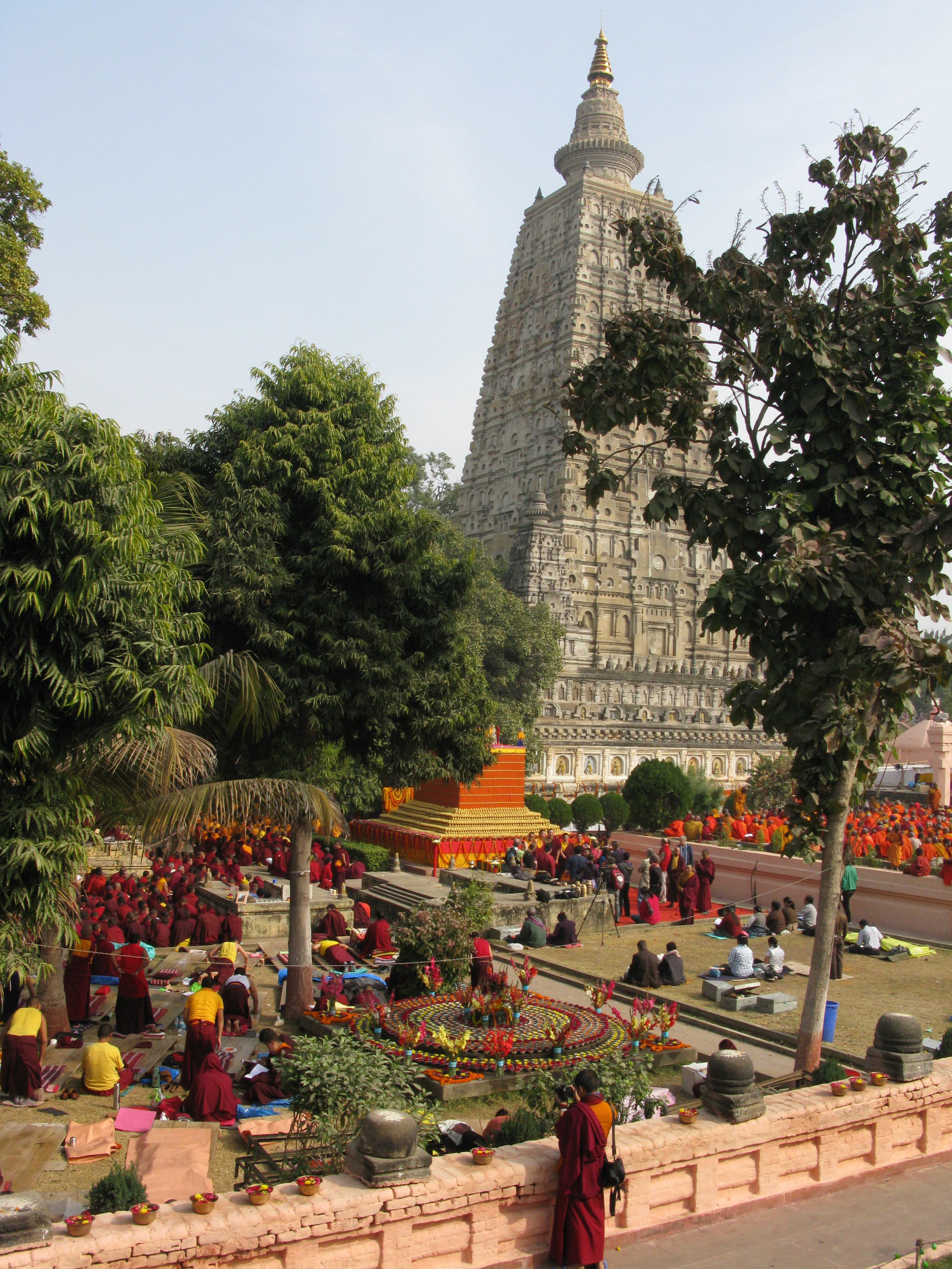 The Mahabodhi Temple seen from the upper most path almost 1/2 way around the temple. A timeless tableau of monks offering prayers and mantras for peace. The Vajrasana throne of the Buddha is under the Pipal tree immediately behind the Temple. Pilgr