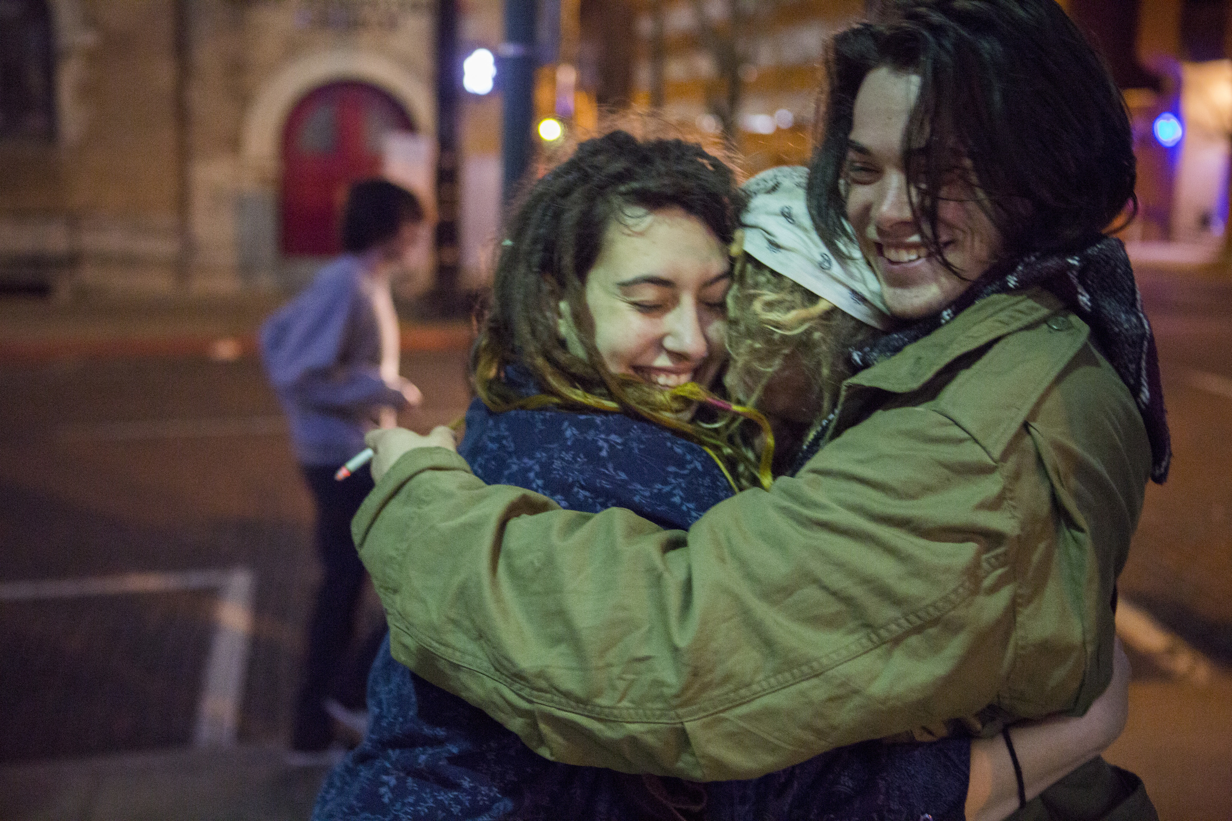  Kima, Solar, and Riley hug while Spiral and others play music on Court Street in Athens. 