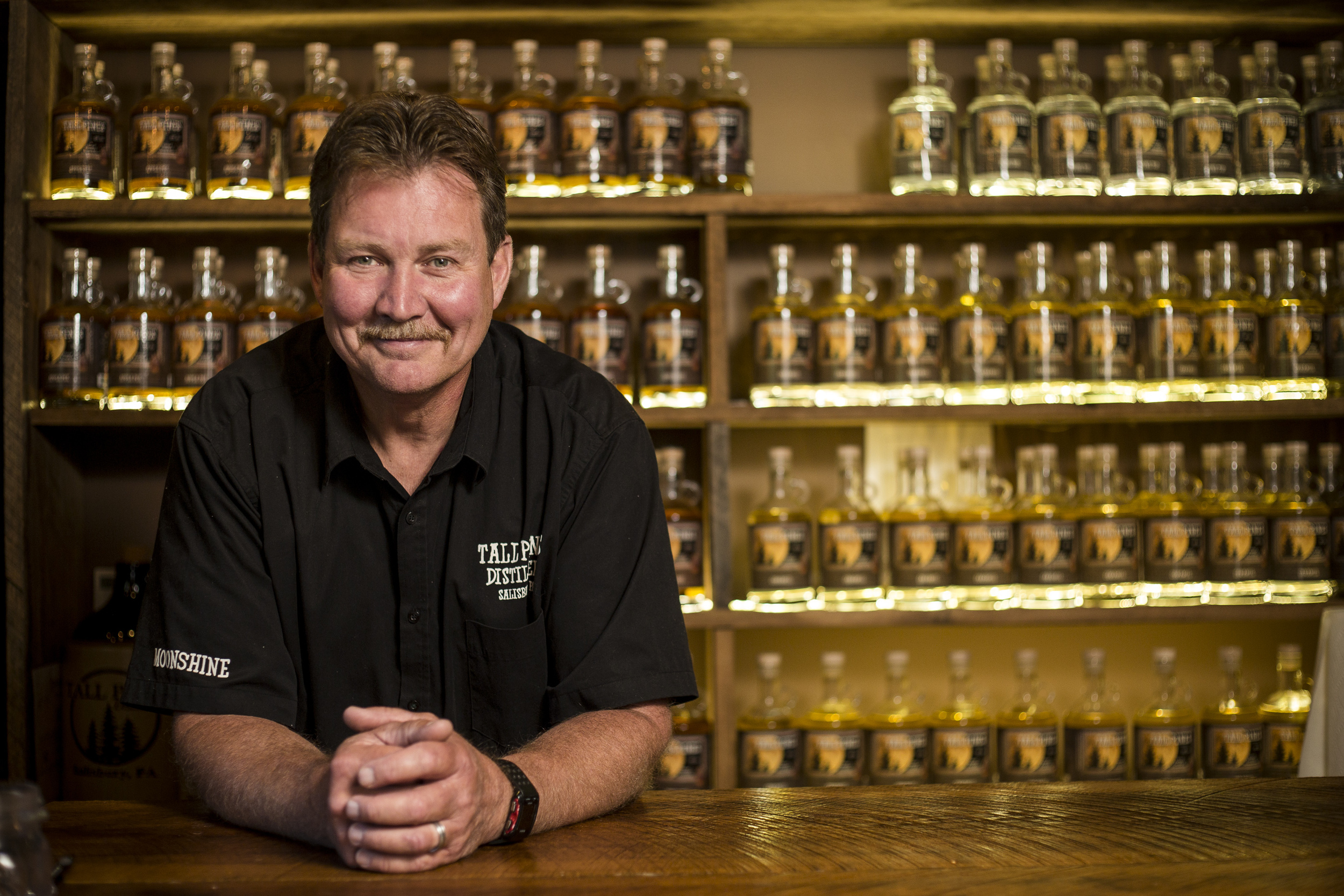  Tall Pines Distillery co-owner Keith Welch stands for a portrait in front of some of the distillery's moonshine in Salisbury, Somerset County, on Monday, July 11, 2016. The distillery claims to be the first legal moonshine distillery in Somerset Cou