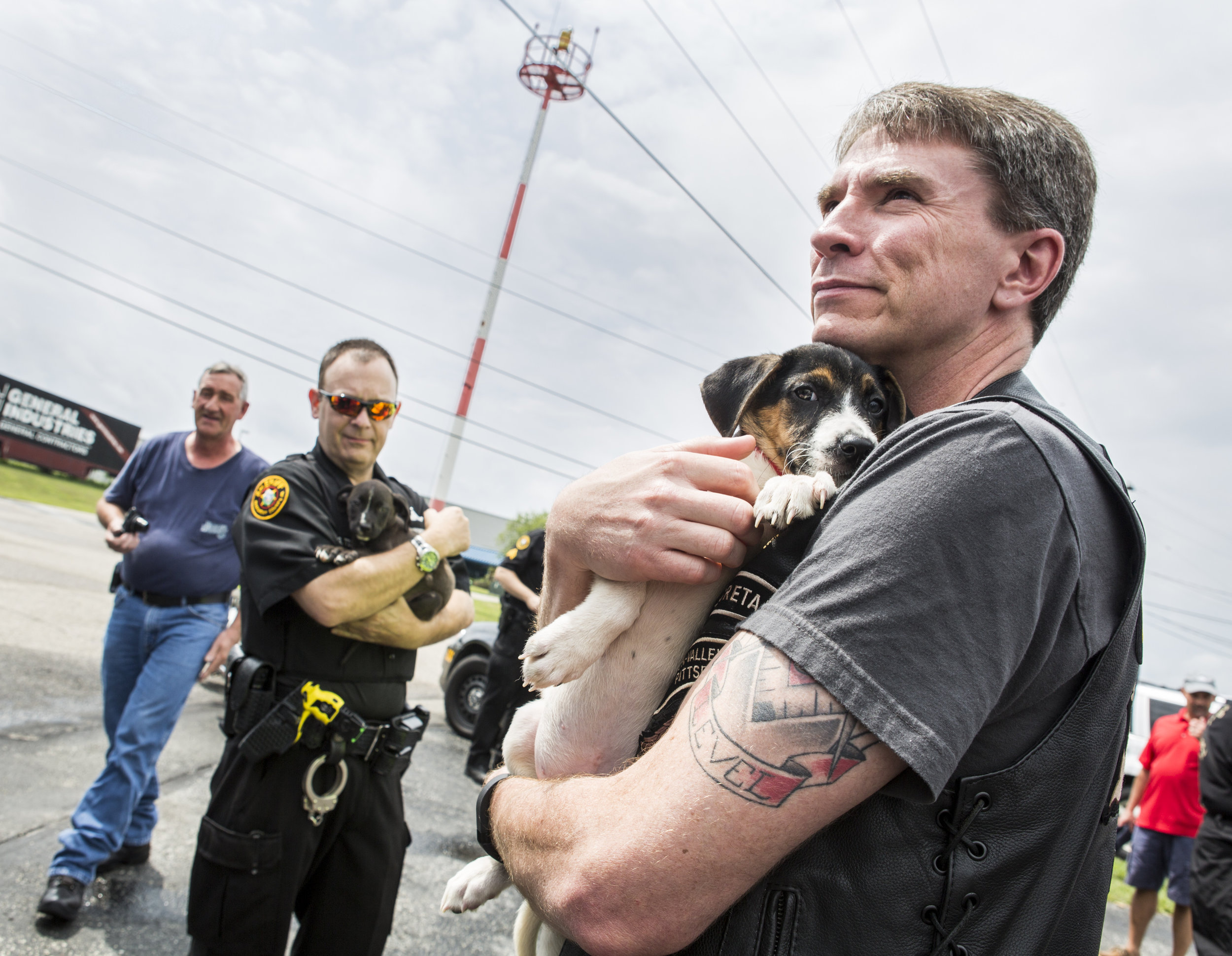 John Schivik of the Mon Valley Harley Owners Group greets a puppy after a long ride from Tennessee at the Rostraver Airport on Saturday, July 30, 2016. The dogs were being taken back to Hot Metal Harley-Davidson for a fundraiser and were being put u