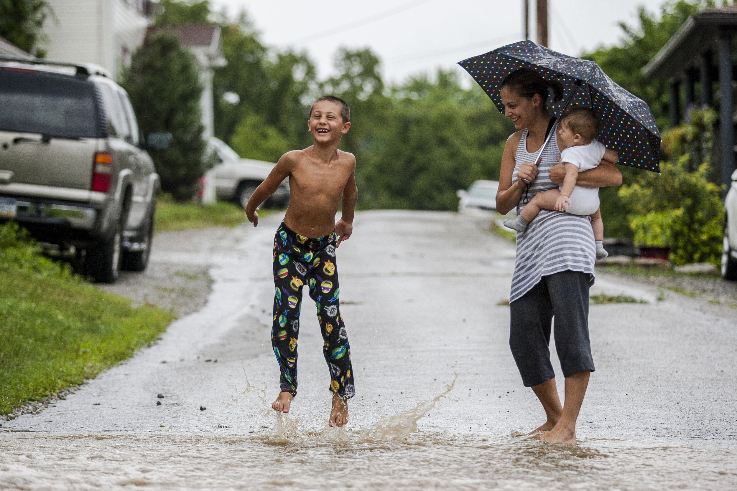  Robert Repovz, 6, splashes through rain water running across First Street while his mother Anita and baby sister Gabriella watch in New Stanton, Pennsylvania, on Saturday, July 30, 2016. 