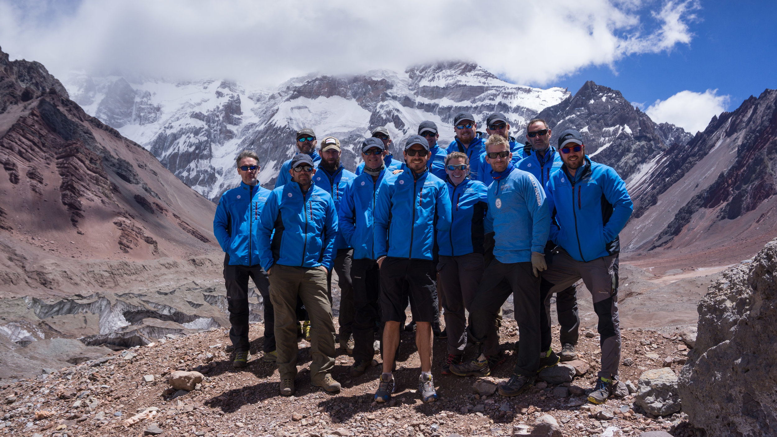 The imposing south face of Aconcagua looms behind the team.