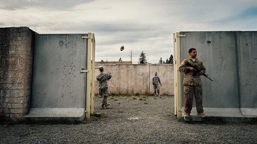 1st place in the Sports Photography category: Two soldiers play catch with a football while a fellow soldier watches the perimeter of the training grounds during the Expert Field Medic Badge course at Joint Base Lewis-McChord, Wash., Sept. 24, 2015. The EFMB is the non-combat equivalent of the Combat Medical Badge and is awarded to medical personnel of the U.S. military who successfully complete a set of qualification tests. IMAGE: SENIOR AIRMAN JORDAN A. CASTELAN, USAF