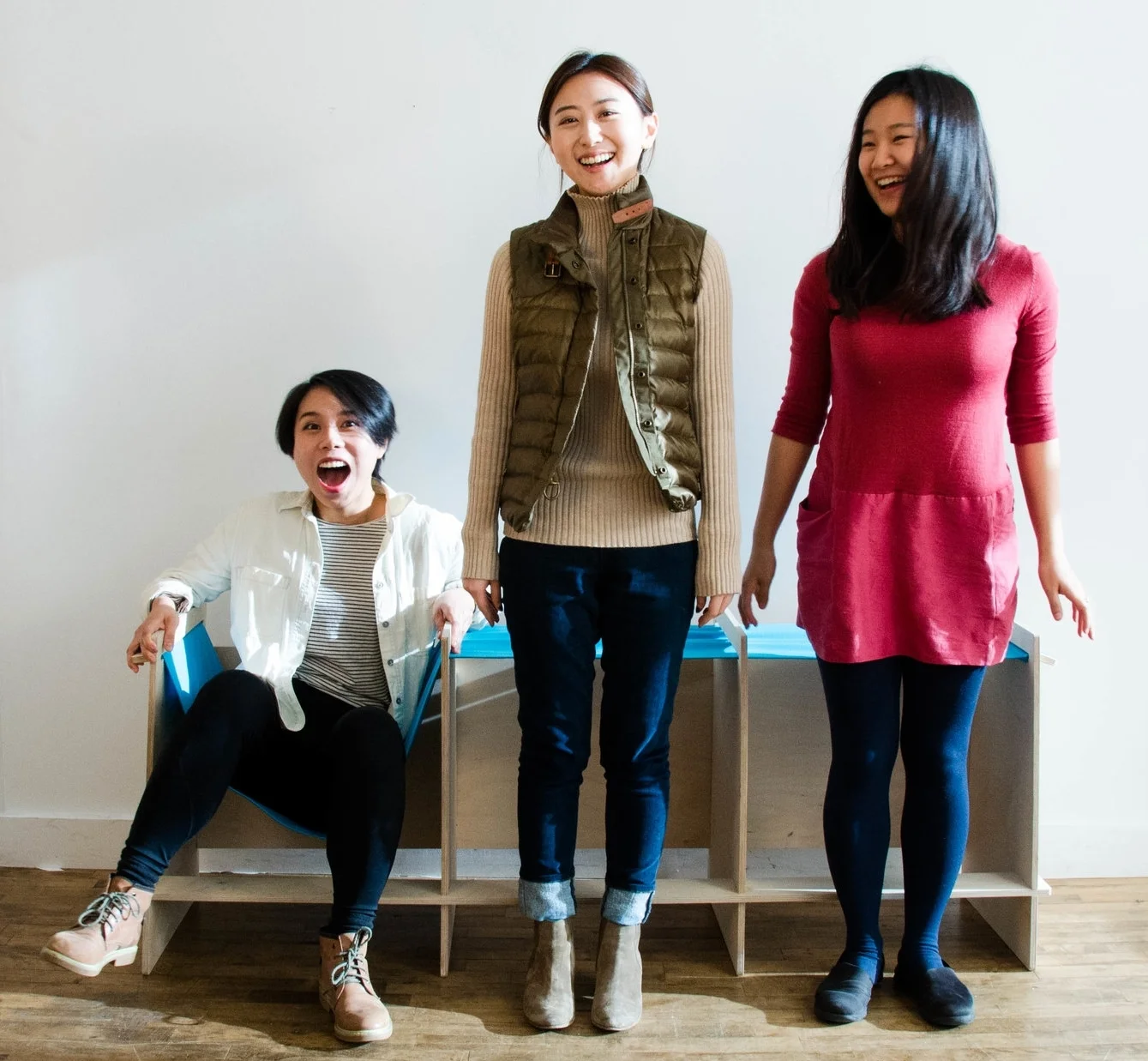 Three young, smiling women, one sitting, two standing
