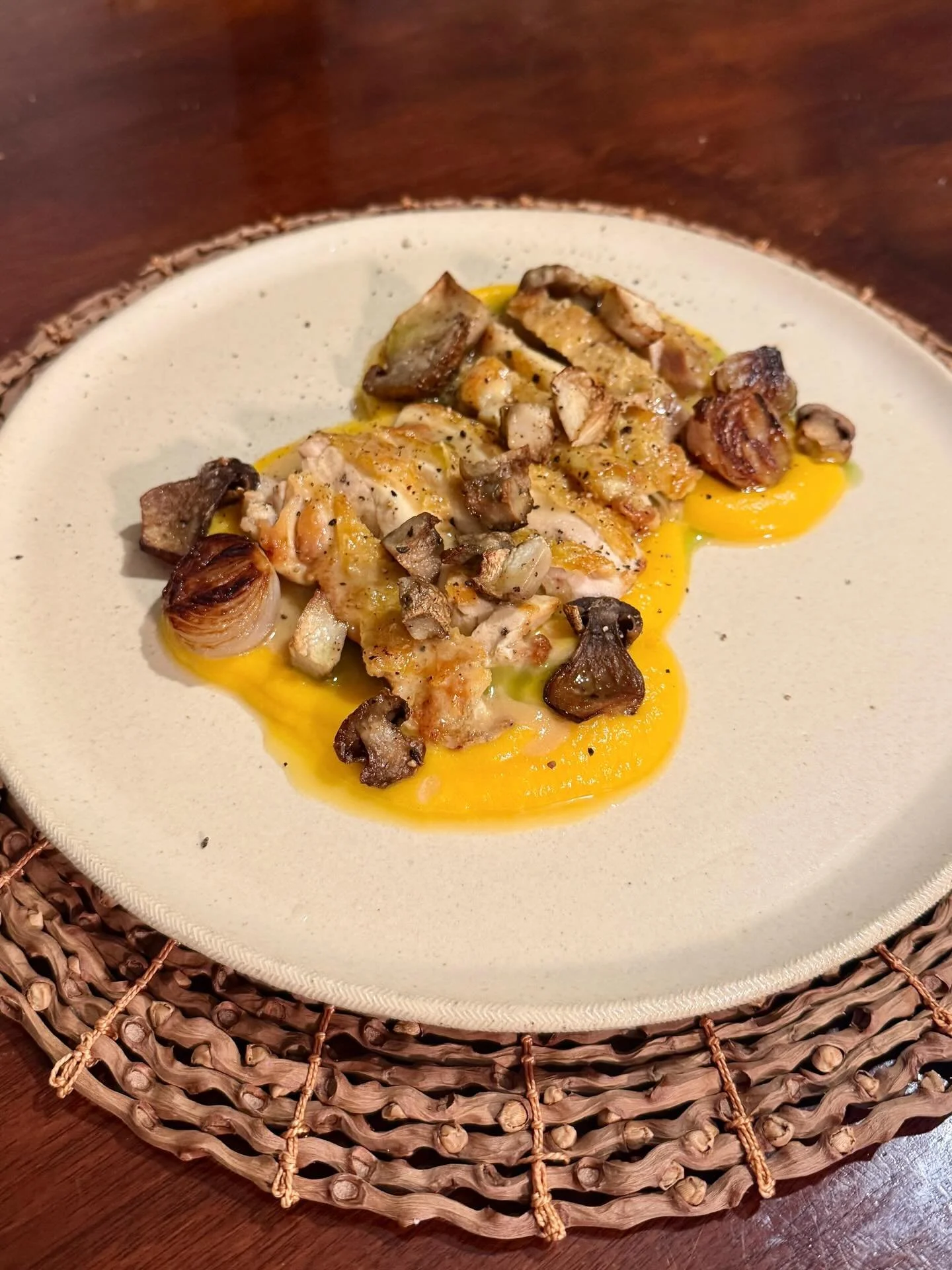 Chicken thigh with pumpkin pur&eacute;e, pan sauce, charred onions, ceps, and fig leaf oil.