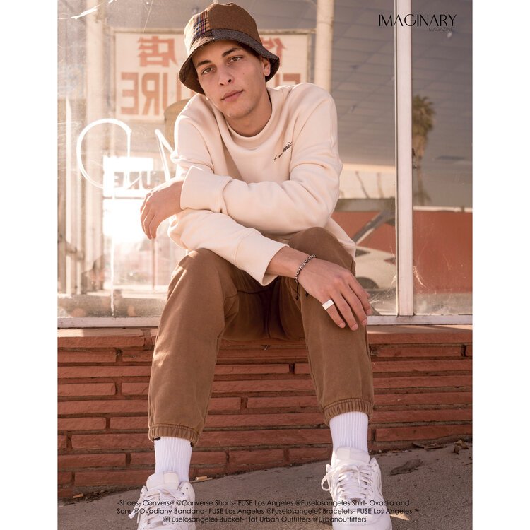  Male model poses in front of storefront in street-style editorial shoot. Styled by Emily Burnette. 