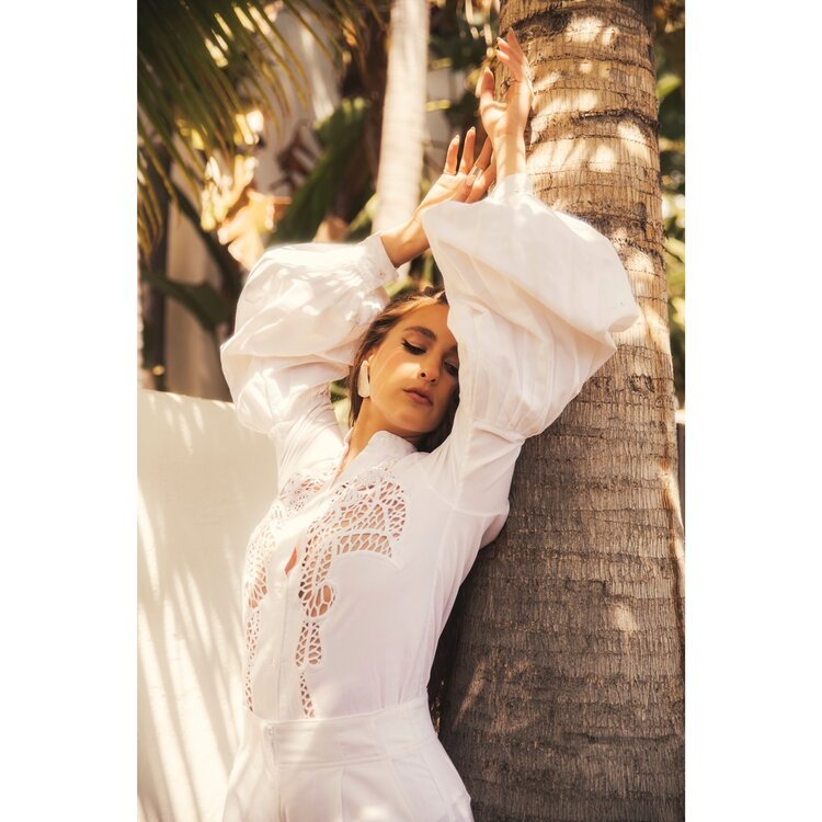  Singer Evangelia in white puff-sleeve dress poses by palm tree. Styled by Emily Burnette. 