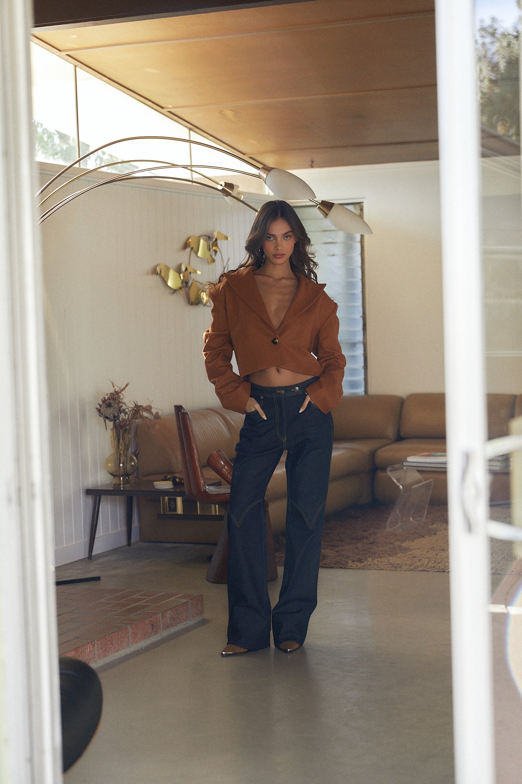  Model shot in mid-century home wearing cropped blazer, and dark blue denim with boots. Styled by Emily Burnette. 