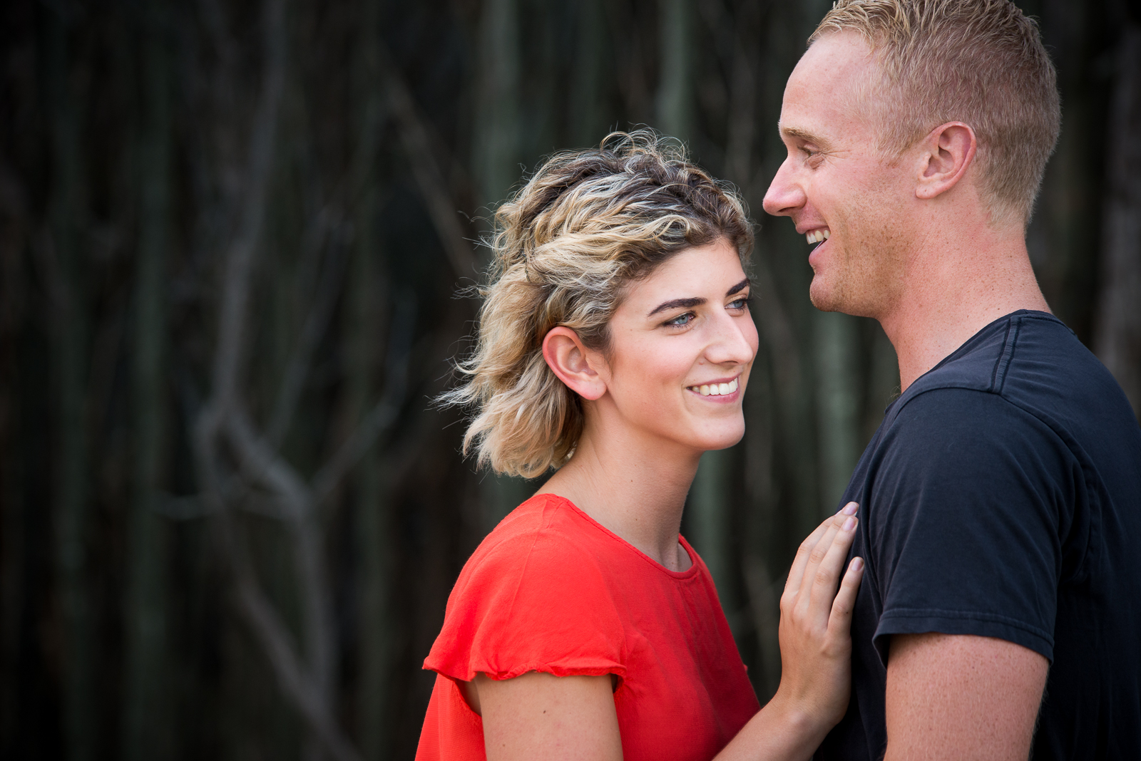 Engaged couple against dark tree background