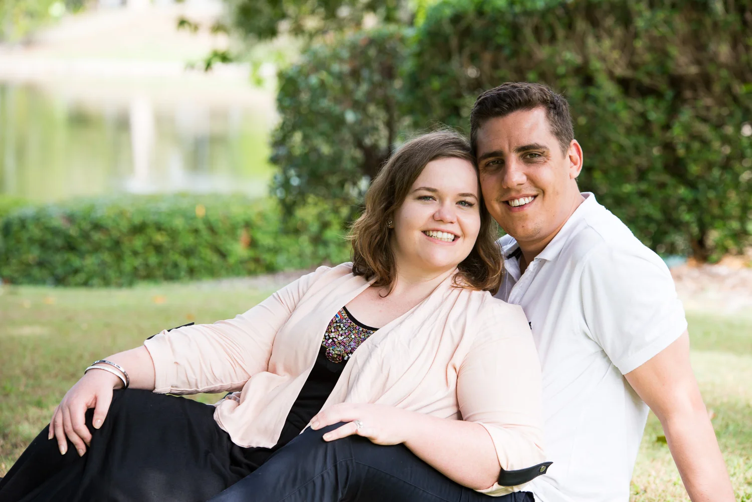 Outdoor portrait of young married couple sitting in park