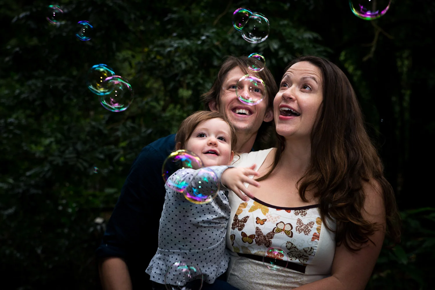 mum, dad and daughter catching bubbles