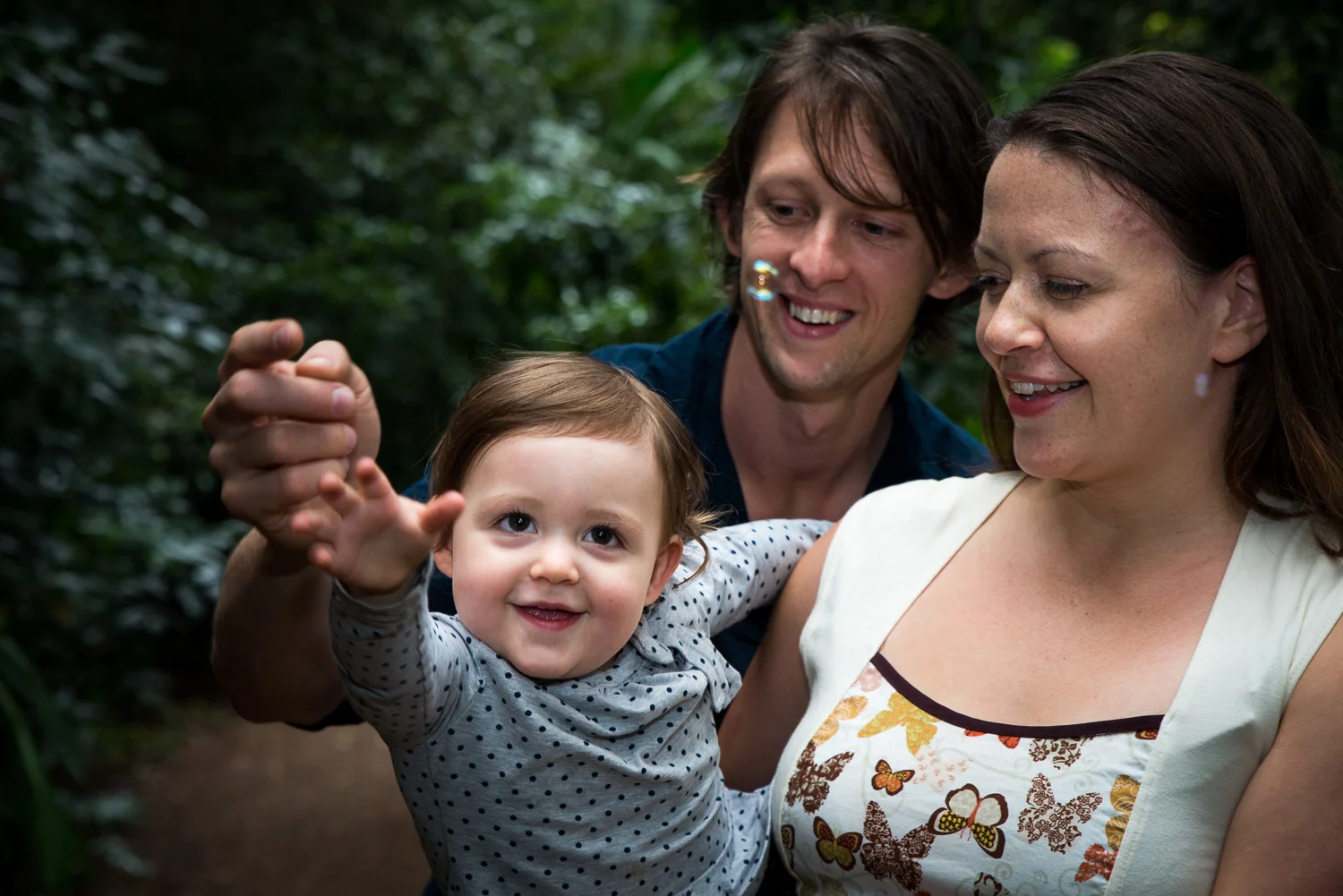 mum dad and daughter catching bubbles