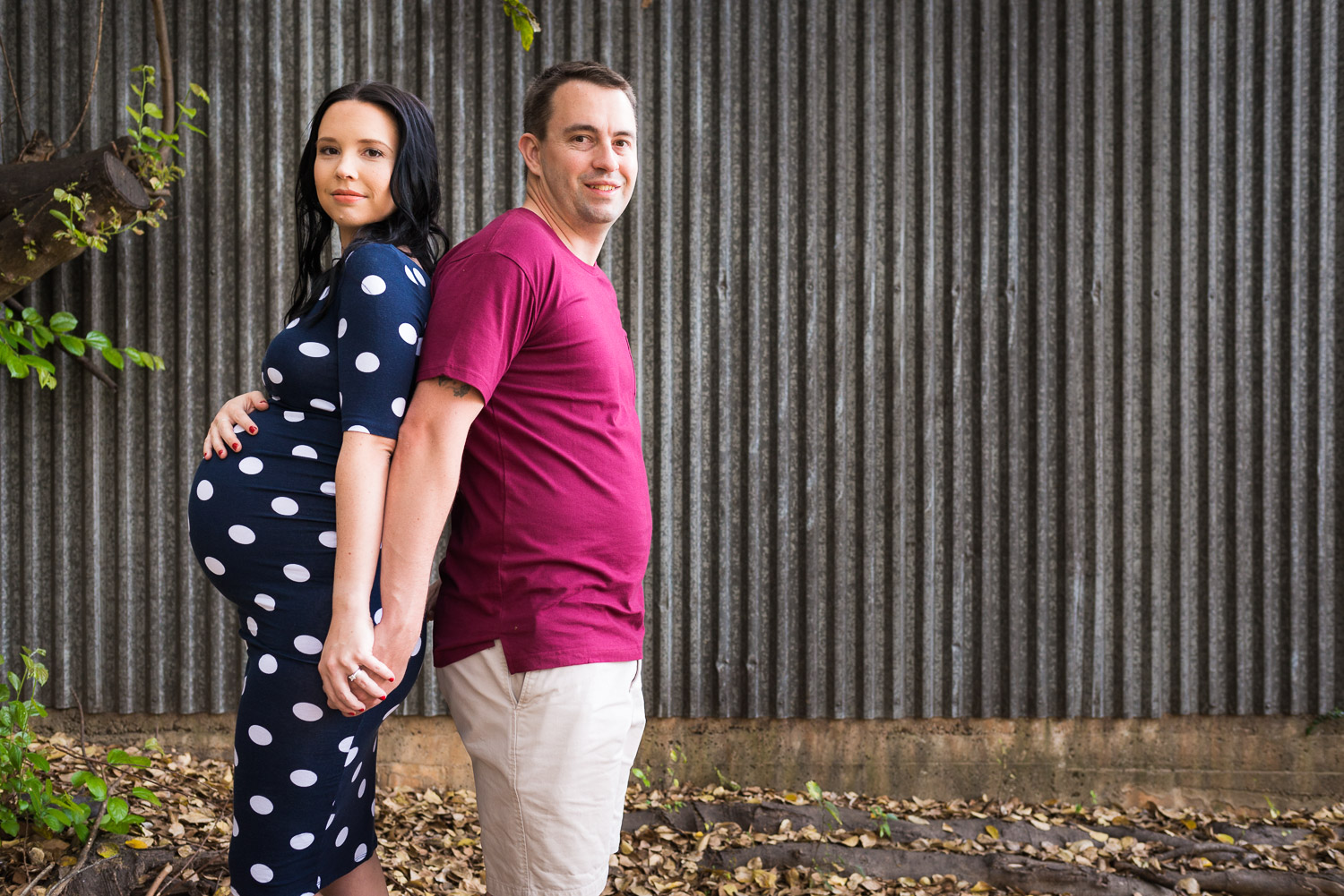Maternity portrait in urban scene of couple standing in front of tin wall in Caboolture