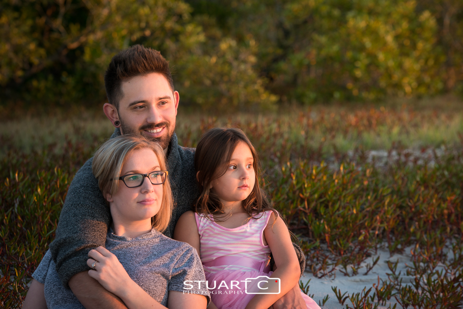 family on beach with green background at sunset