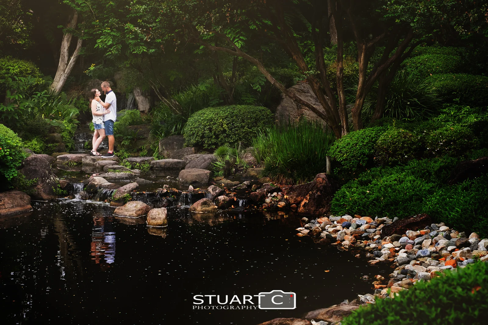 Casey and Gary standing on the rocky pathway in the middle of the Japanese Garden at Mt Cootha Botanical gardens during their engagement photo shoot