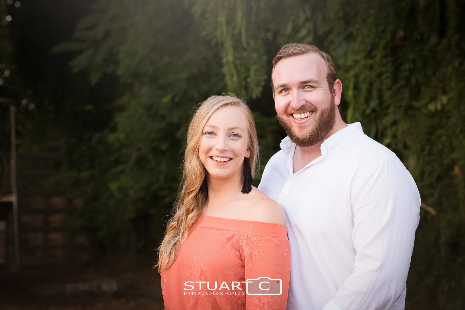 Close up Portrait of newly engaged couple Jannika and Matt against dark green background in the main street of woodford