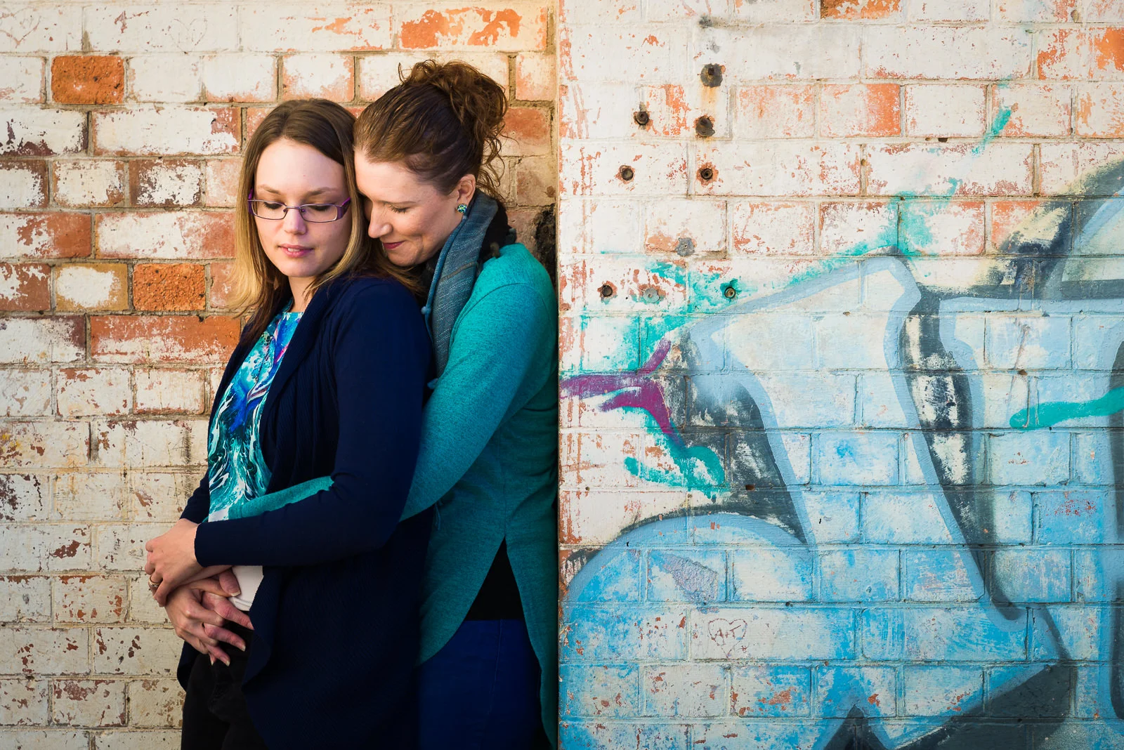 LGBQTI engaged couple at brisbane powerhouse standing in front of brick wall with graffiti