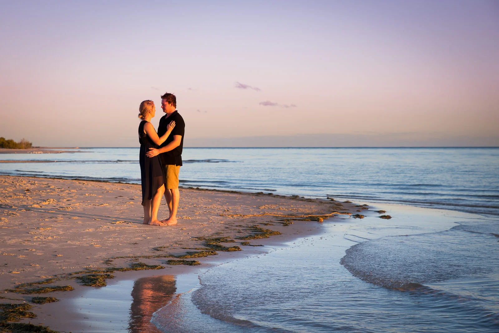 Engaged couple embracing on the beach at Bribie Island during sunset