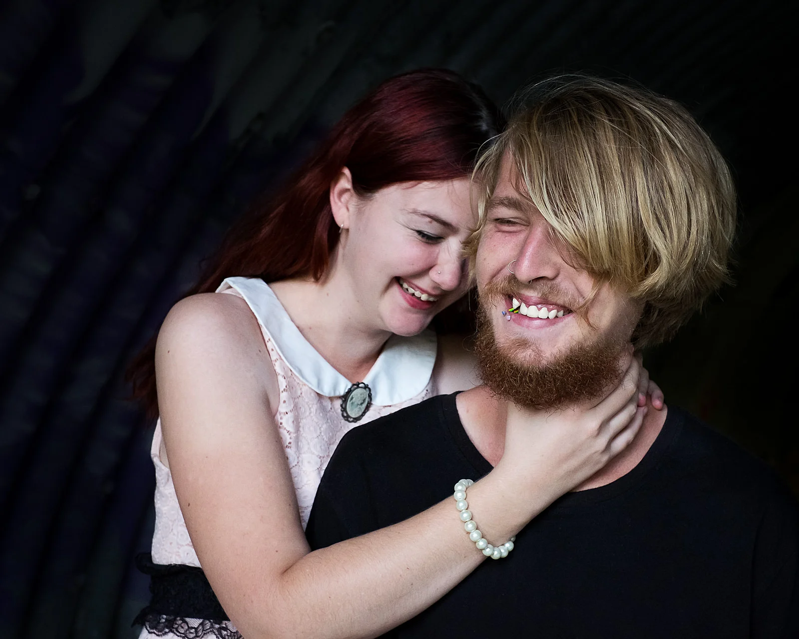 Engaged couple playing up, dark natural light in urban setting