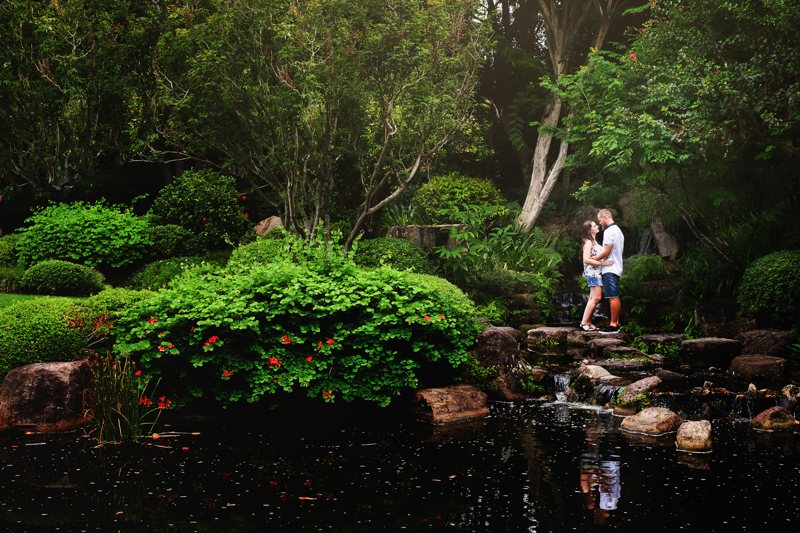 engaged couple standing on stepping stone in front of Japanese lake at Mt Cootha Botanical Gardens