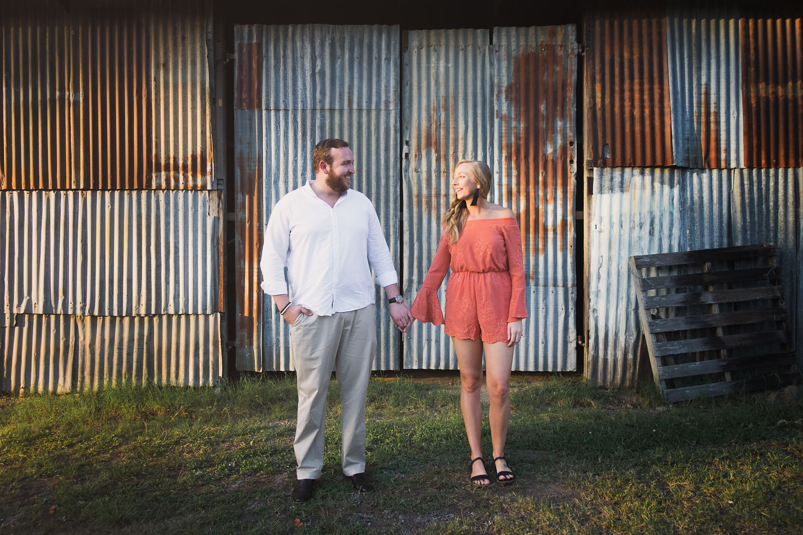 engaged couple standing in front of rusted tin wall in Woodford