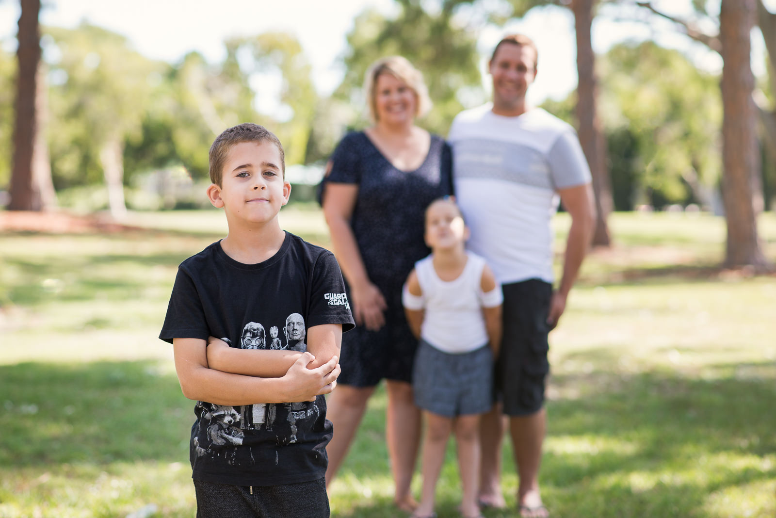 Family of four wearing white, blue and black combinations for outdoor family portraits in local park