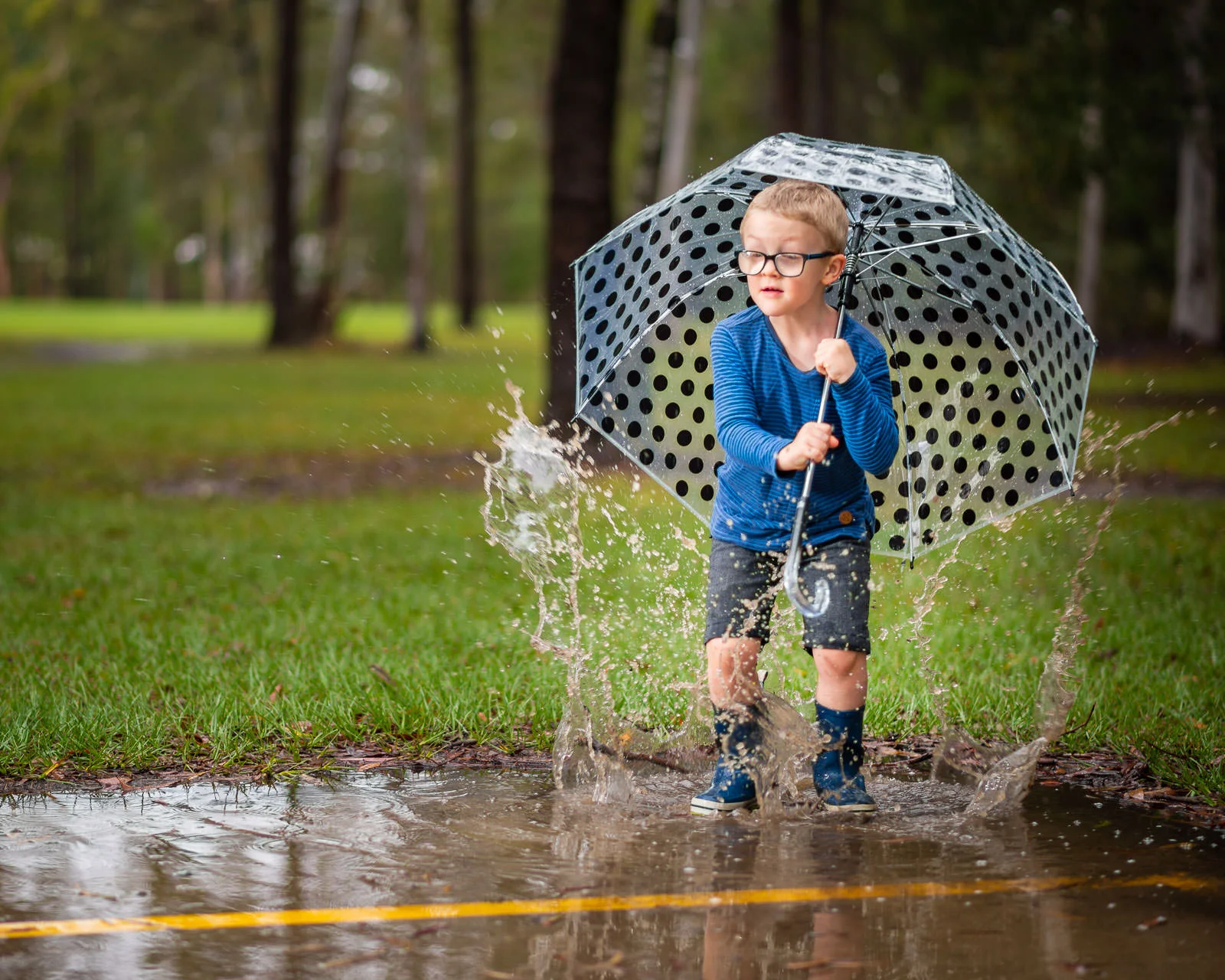 Young boy jumping and splashing in puddles during outdoor portrait photos | Caboolture family photography