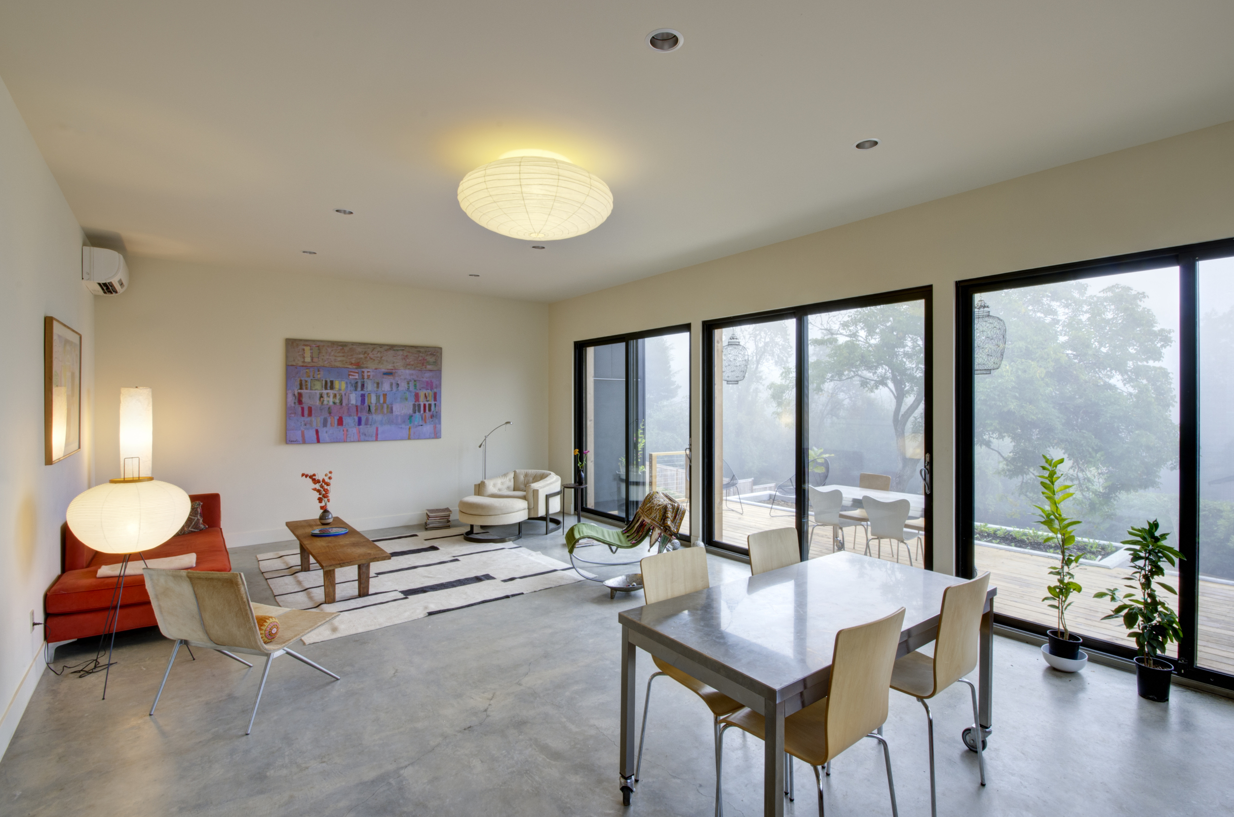 The open living/dining/kitchen area is edged by three big eight-foot by eight-foot sliding doors, which fill the room with light, give a sense of spaciousness, and allow easy access to the adjacent wood deck. All doors and windows are triple-glazed for indoor comfort.