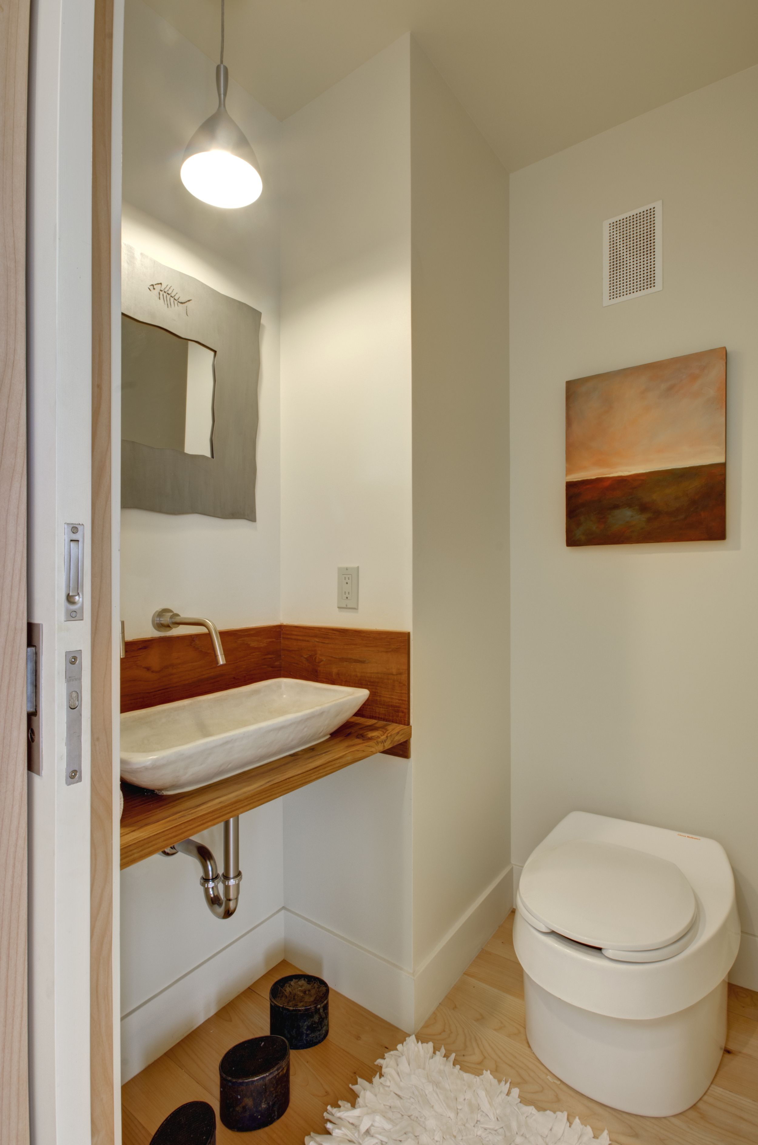 The half-bath features a composting toilet, a handmade sink by the owner's friend, and an upcycled wood vanity (repurposed from the owner's old coffee table).