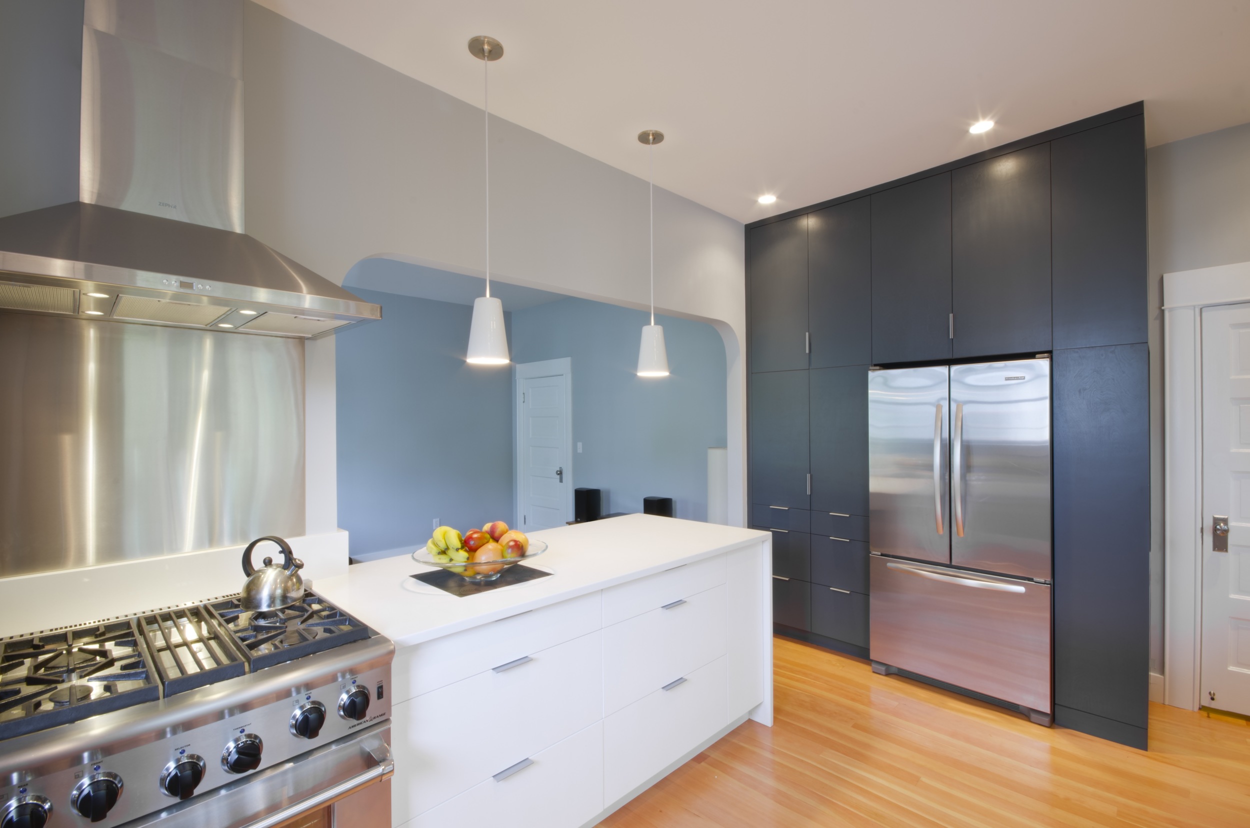 Custom cabinets optimized storage in the kitchen. Full-height cabinets that surround the refrigerator allowed the rest of the kitchen to go without upper cabinets, which makes the kitchen feel more open and airy.