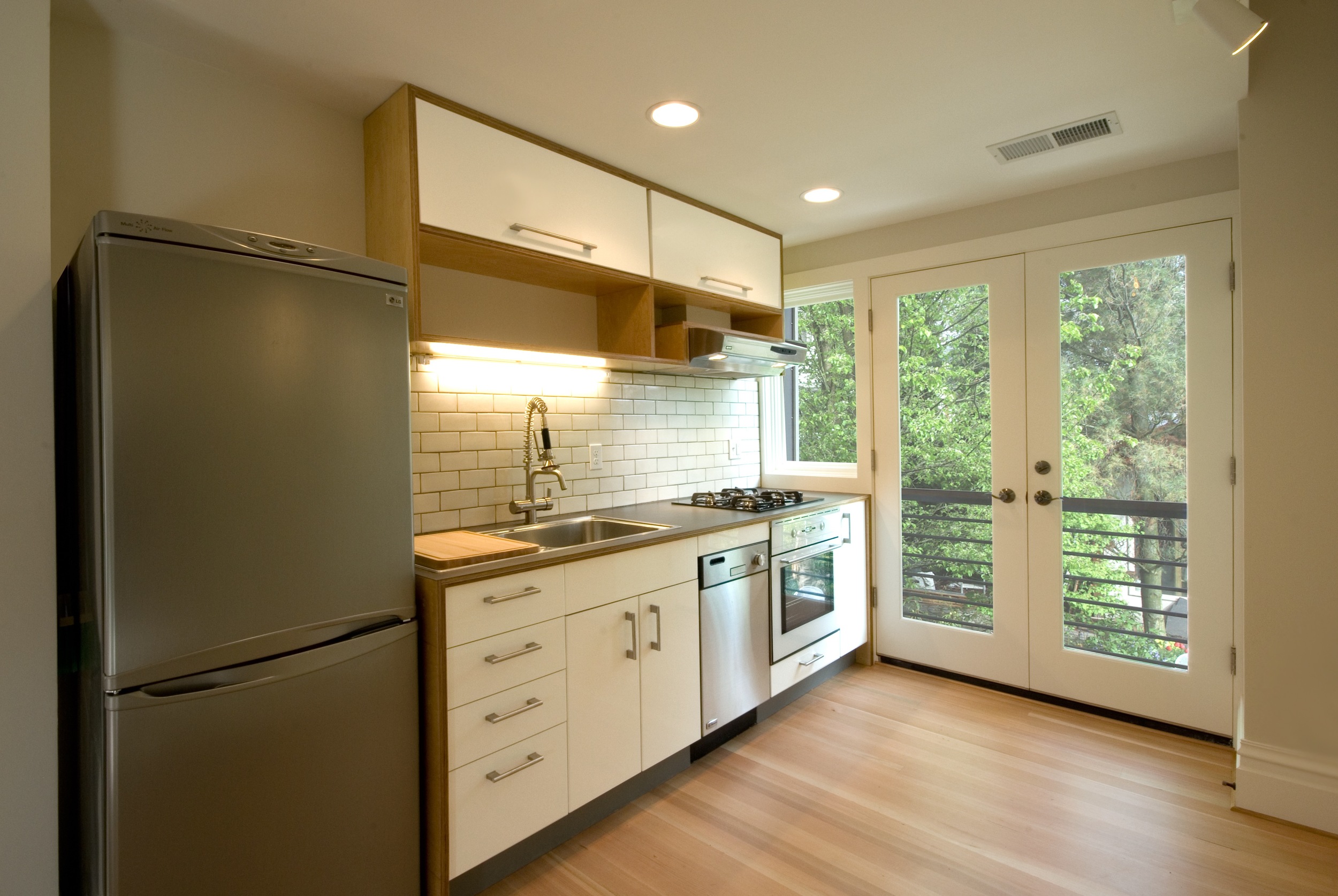 New french doors and a balcony fill the upstairs unit's kitchen with light and views to the shared backyard.