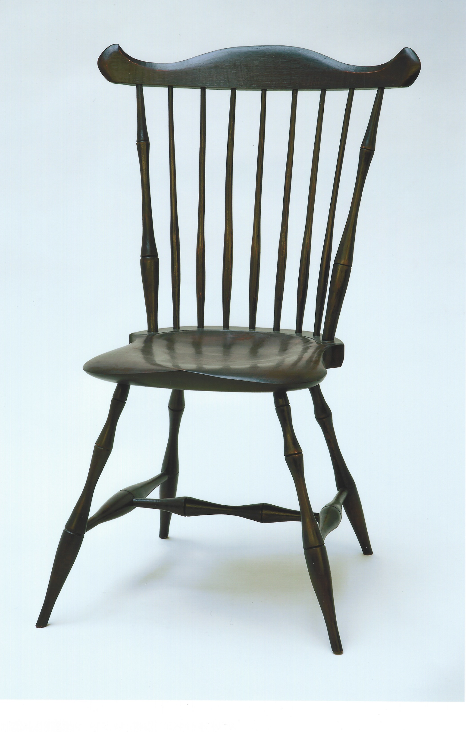 This Windsor Chair has maple legs and stretchers, pine seat and white oak back. The legs, stretchers, and back were made with green wood. Clicking on the chair photo will show that the parts were cut and split from logs and then shaped, turned and steam bent into chair parts. Green wood is used to add strength to the chair. The finish is black over red milk paint and an oil and urethane top coat. The black milk paint is burnished until the red just starts to show through the black. This is done to give the chair a well used appearance. This chair is sold, but we would be glad to build one for you. The price is $1800.00