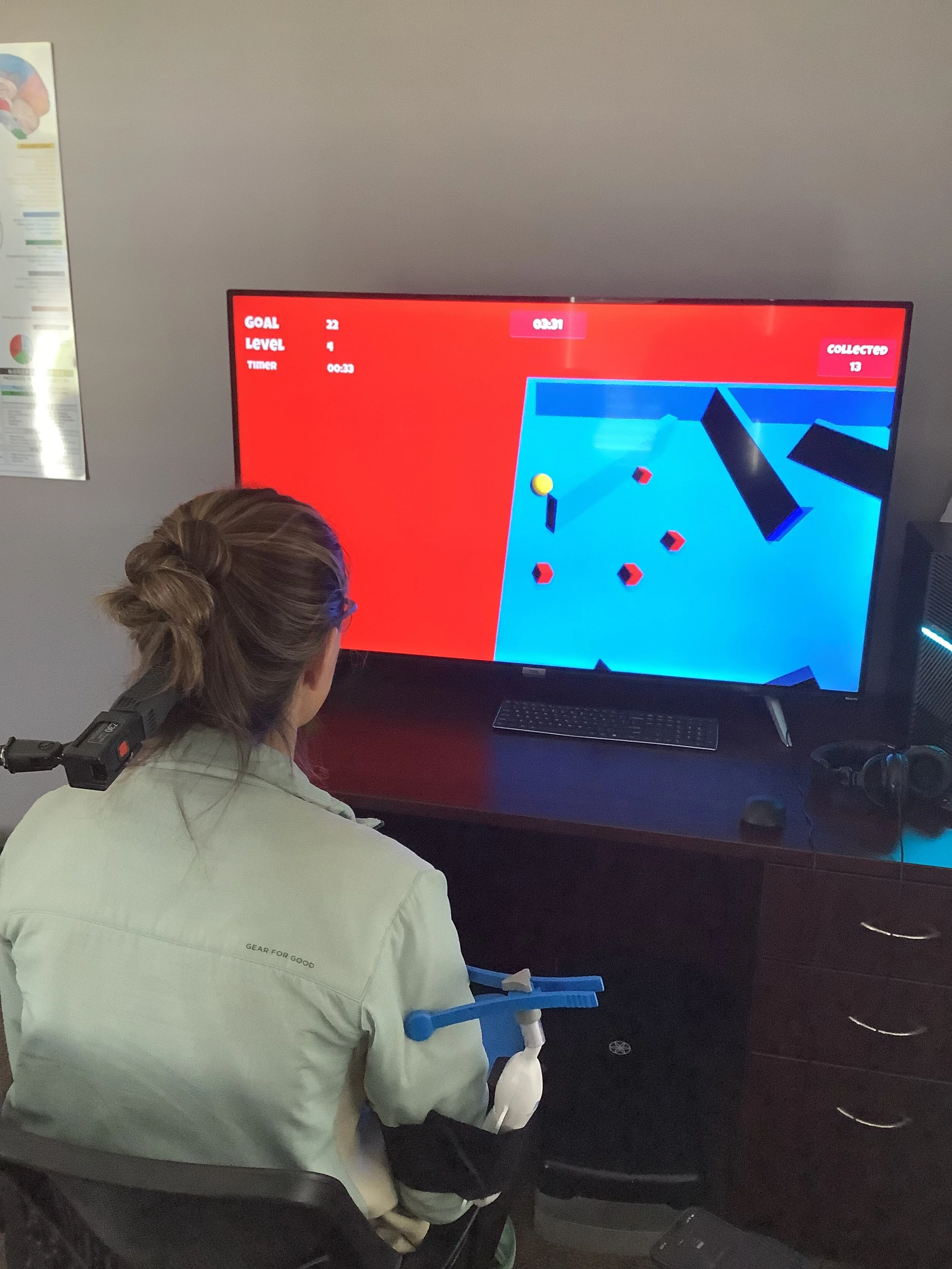 Woman playing a virtual reality ping pong game with a controller and a headset on a desk in front of a computer monitor.