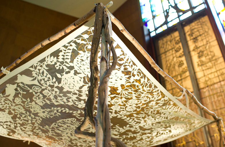 this chuppah frame is made out of branches; the canopy is a piece of cloth tied to them.