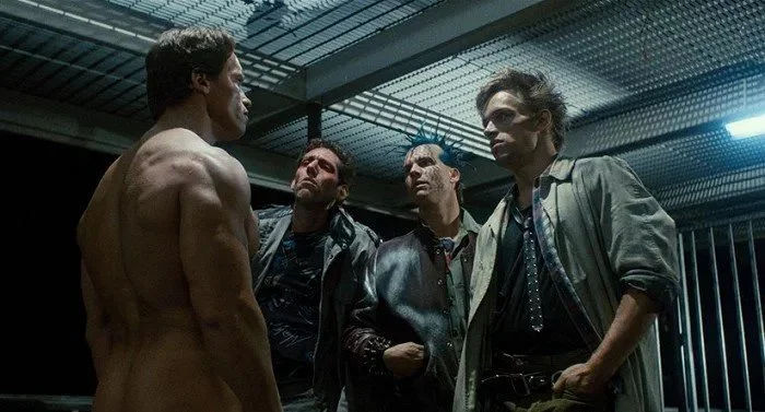 Three 80s movie punks, including Bill Paxton and Brian Thompson, try to maintain eye contact with a naked Arnold Schwarzeneggar