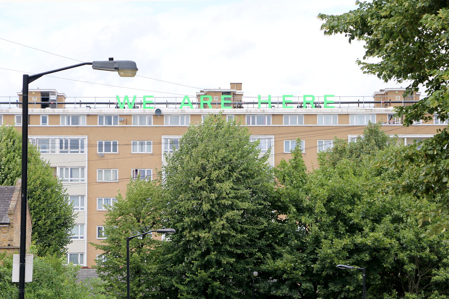 Jessie Brennan WE ARE HERE (2018), text installation (situated on the roof of Heron House), Pelican Estate [view from Denman Road].jpg