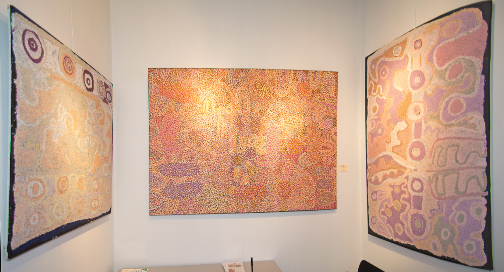 A droite et à gauche, se faisant face, l'artiste Aborigène d'Australie, Angkaliya Curtis dans deux œuvres aux tons pastels autour de la mythologie du rêve des sept sœurs. Au centre une toile de l'artiste Ngupulya Pumani Margaret du centre d'art de Mimili Maku où les signes évoqués s'évanouissent derrière un pointillisme de circonstance pour atténuer la portée d'éléments sensibles.