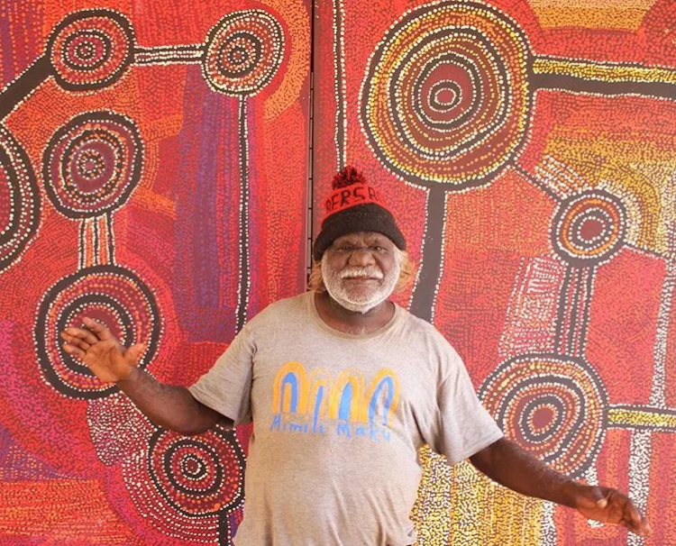 Portrait de l'artiste Willy Mutjanji Martin devant une de ses œuvres. © Photo : Mimili Maku Arts with the courtesy of the artist.