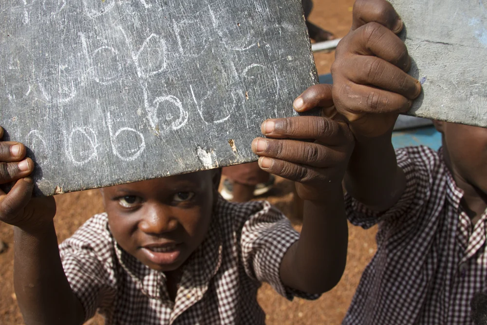 A student at Street Sisters Creche, Acrra, Ghana holds up a school room slate board. (Photo by Alyssa Nedrow)