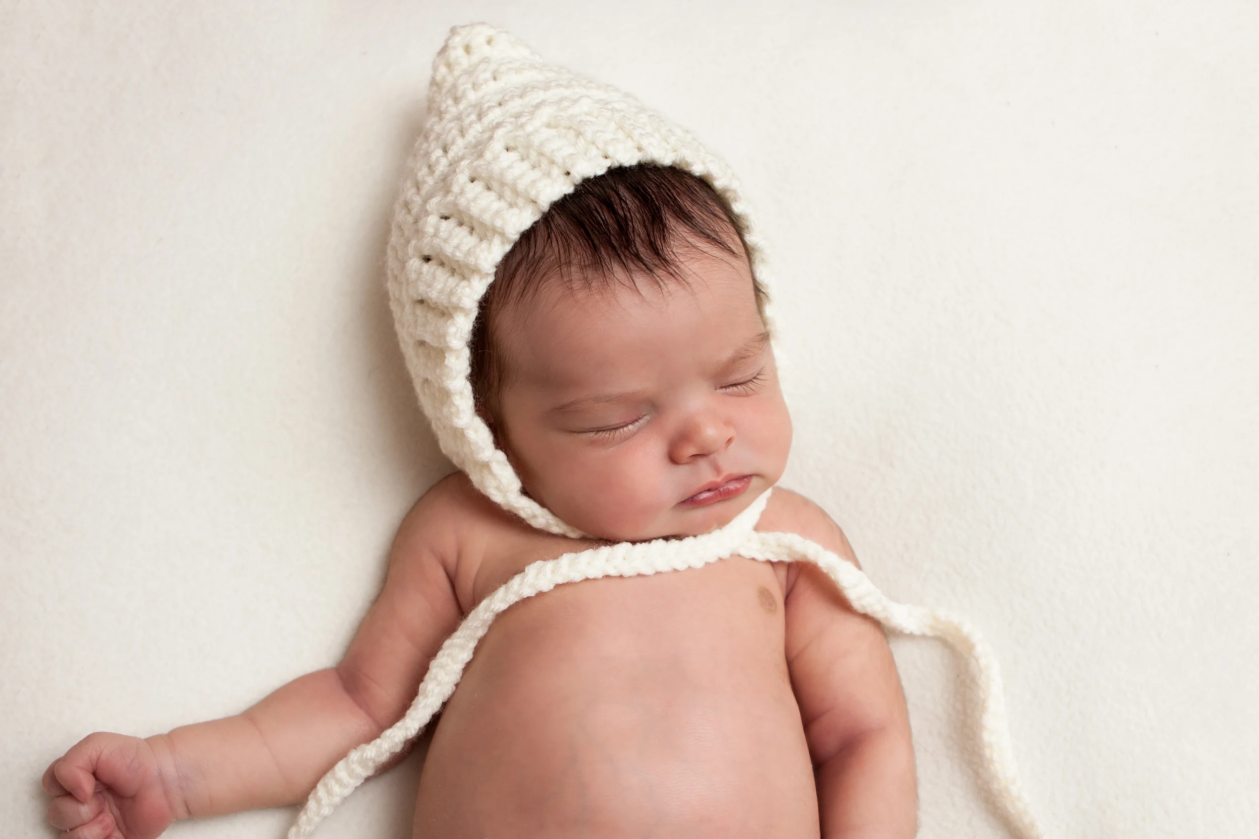 Newborn baby girl white blanket creme bonnet, Westchester County, NY Newborn Photographer Amanda Noelle Photography.