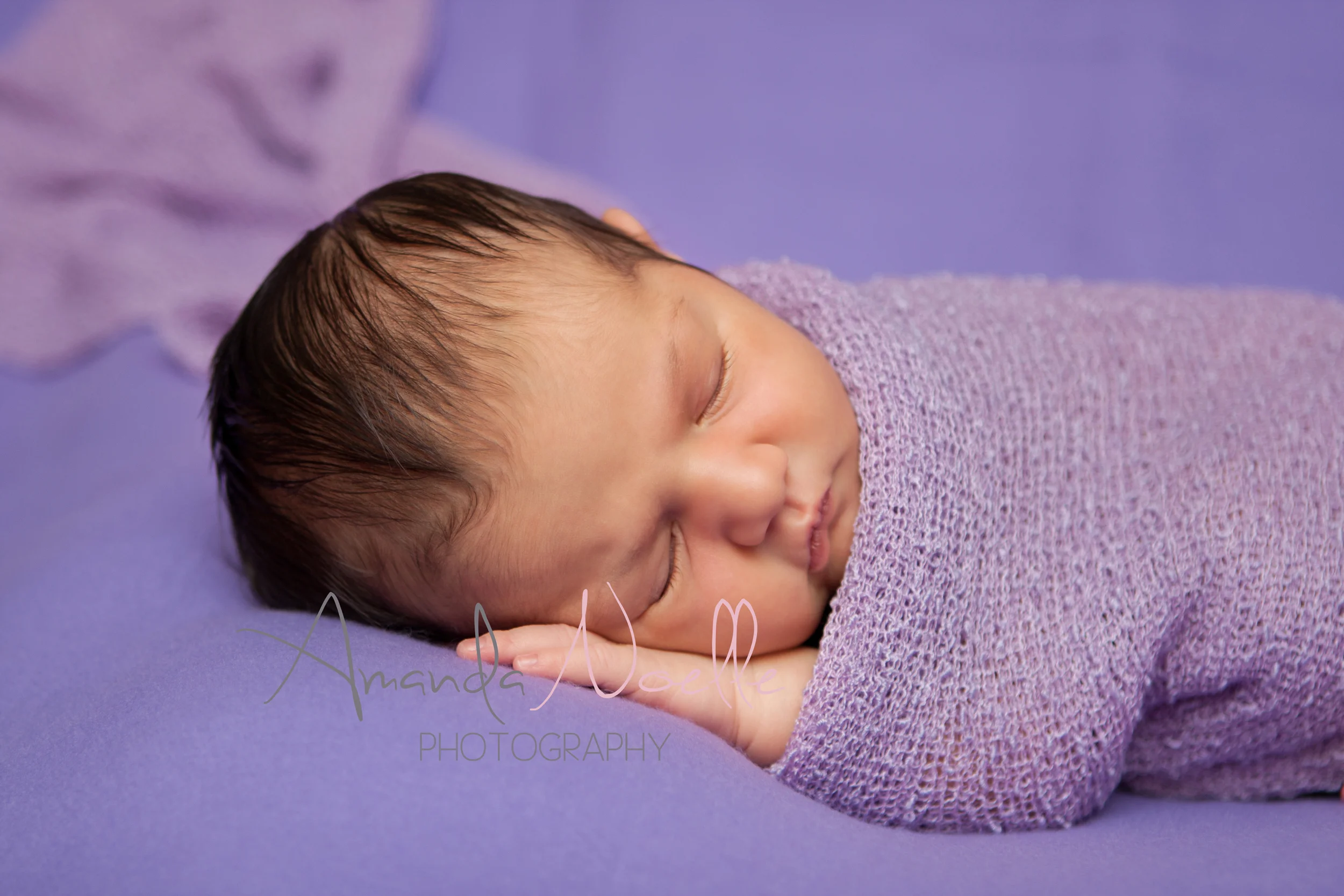 Newborn baby girl, purple background fabric, purple lilac stretch wrap draped, sleeping pose on beanbag, by Westchester, New York Newborn Photographer, Amanda Noelle Photography