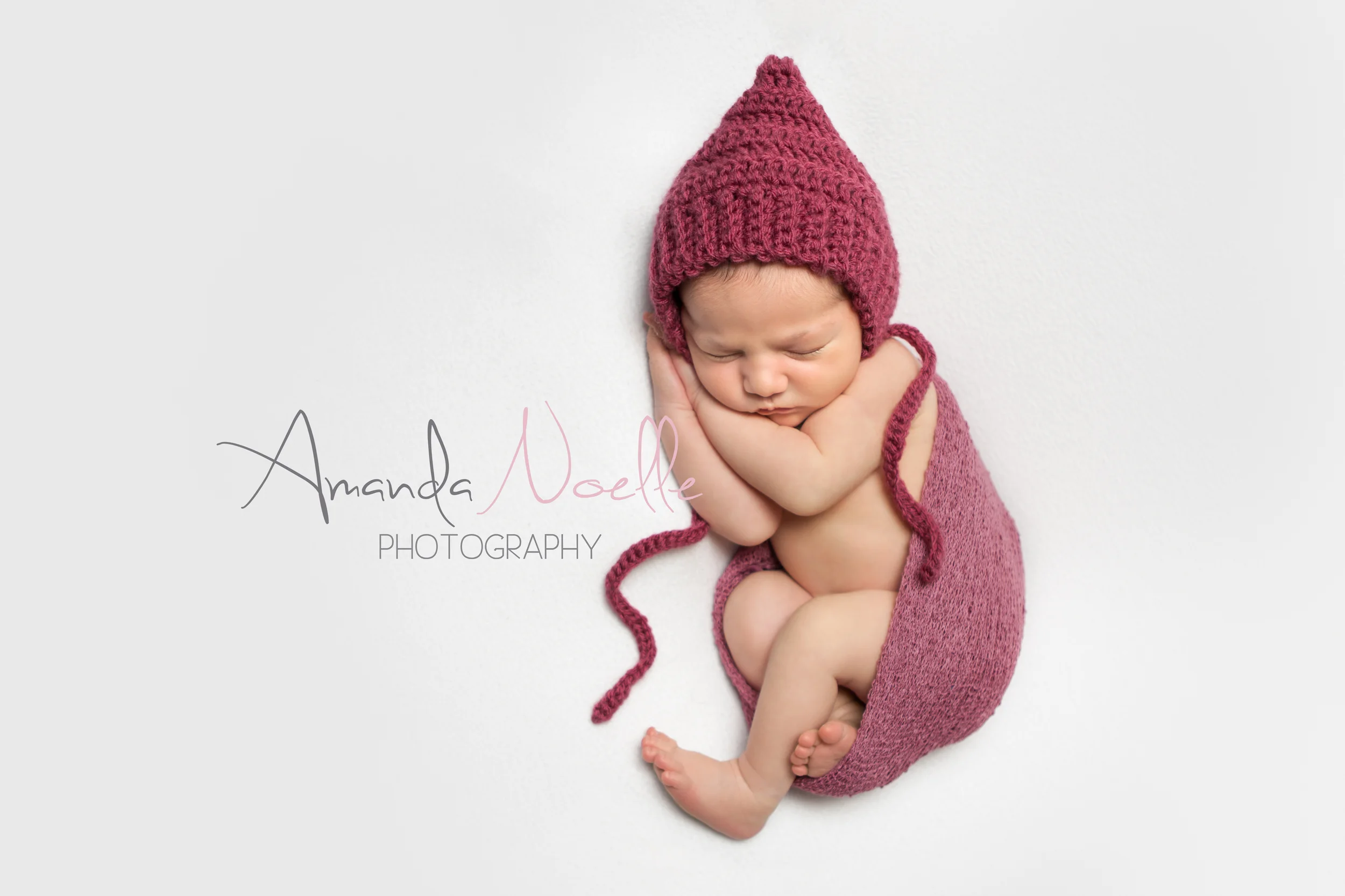 Newborn baby girl, white background fabric, dark pink maroon crochet bonnet, stretch wrap, sleeping pose on beanbag, by Westchester, New York Newborn Photographer, Amanda Noelle Photography