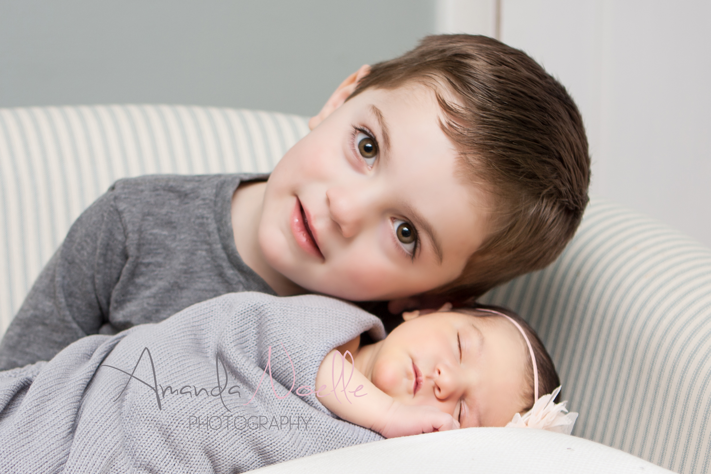 Newborn baby girl, big brother toddler, sibling photography, sitting in chair, newborn on pillow, grey color scheme with pink headband by Westchester, New York Newborn Photographer, Amanda Noelle Photography