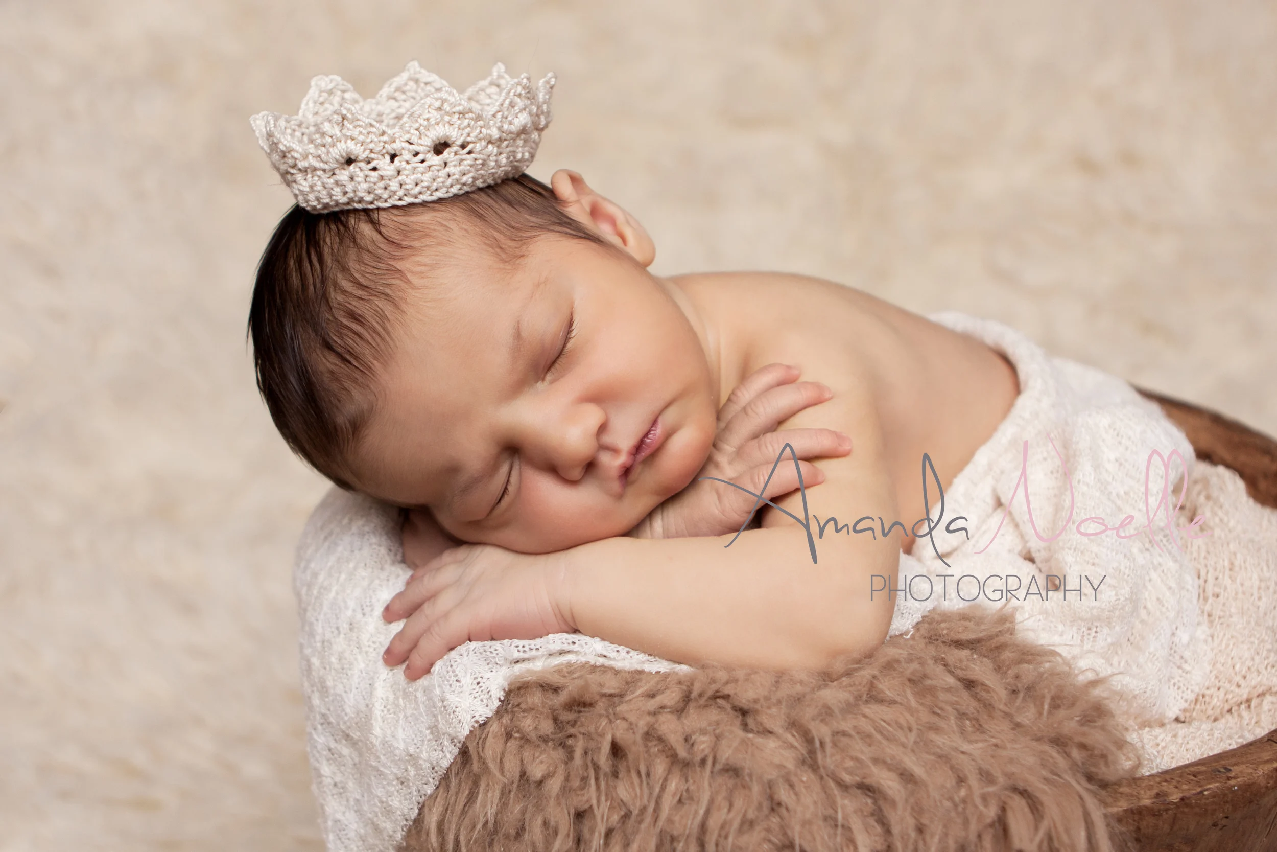 Newborn baby girl, in bucket, layering fabric and fur, tiny crochet princess crown tiara, brown creme, creme rug, sleeping prop pose by Westchester County, New York, Newborn Photographer, Amanda Noelle Photography.